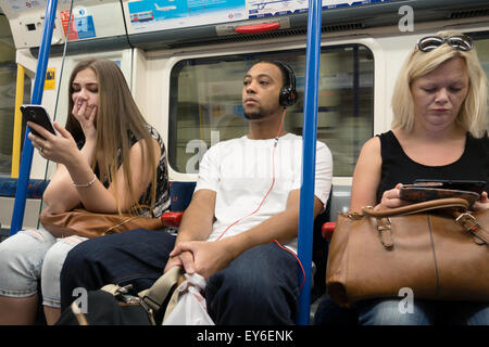 Passagiere auf einer Londoner U-Bahn u-Bahn Zug unter Verwendung moderner Technologien wie Handy, e-Leser und Musik. London-UK Stockfoto