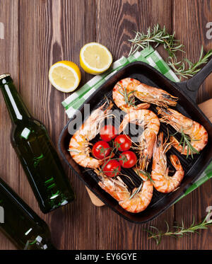 Gegrillte Garnelen auf Pfanne und Bier auf Holztisch. Ansicht von oben Stockfoto