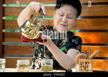 Lokale chinesische Frau zeigt grüner Tee Gießen in eine kleine bar Stockfoto