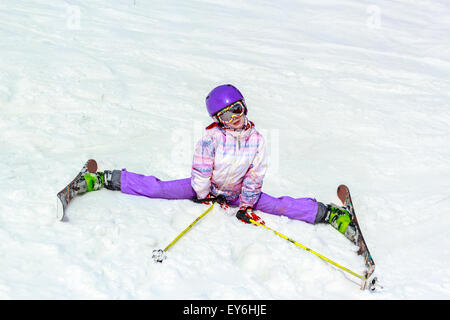 Kleines Mädchen auf den Skiern. Flexible Skifahrer kleines Mädchen gymnastische Übungen auf dem weißen Schnee. Stockfoto