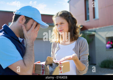 Blick auf eine junge attraktive Frau wütend gegen Lieferung Mann Stockfoto