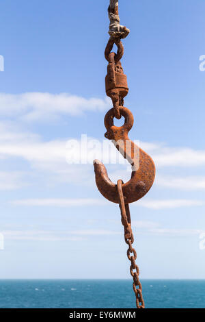 Die gefesselten verrostete Haken eines Krans ist gegen den blauen Himmel und Meer von Portland Bill in Dorset, Großbritannien gezeigt. Stockfoto