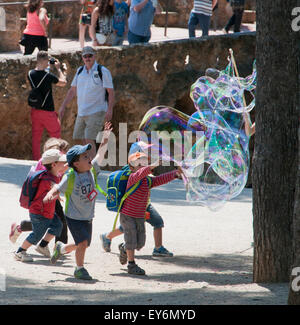 Kinder jagen riesige Seifenblasen erstellt von Straßenkünstler im Parc Güell, Barcelona Stockfoto