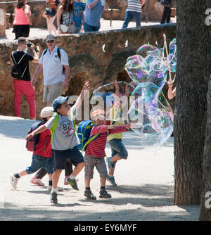 Kinder jagen riesige Seifenblasen erstellt von Straßenkünstler im Parc Güell, Barcelona Stockfoto