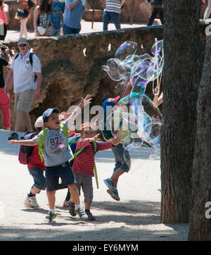 Kinder jagen riesige Seifenblasen erstellt von Straßenkünstler im Parc Güell, Barcelona Stockfoto