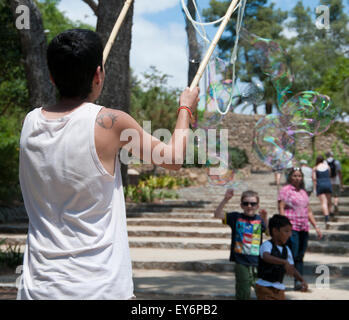 Kind, die jagen riesiger Seifenblasen erstellt von Straßenkünstler im Parc Güell, Barcelona Stockfoto