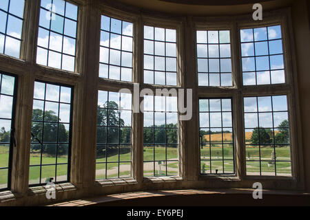 Gartenansicht durch eine verglaste Bogen Fenster in ein Schlafgemach in Kirby Hall, Northamptonshire NN17 3EN Stockfoto