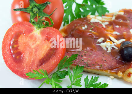 Halbierte Tomaten mit Scheibe Pizza und Petersilie in Backgroundon weiß Stockfoto