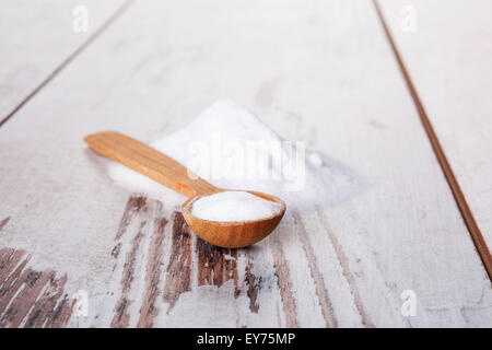 Backpulver auf Holzlöffel auf weißem Holz strukturierten Hintergrund. Stockfoto