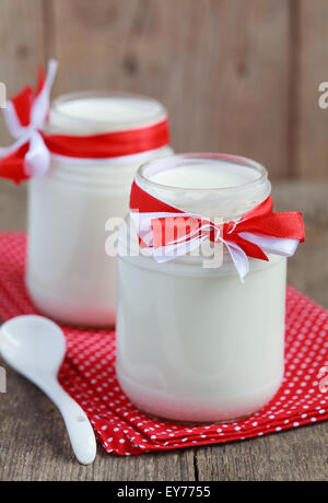 Hausgemachtes Joghurt in zwei kleinen Gläsern auf einem Holztisch mit rotem Tuch, selektiven Fokus Stockfoto