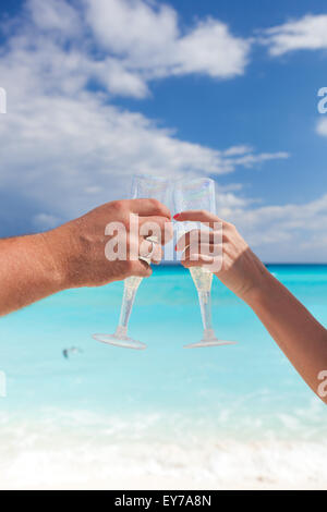 Klingende Gläser mit Champagner am Sandstrand und Meer Hintergrund, geringe Bautiefe Stockfoto