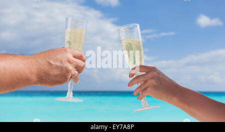 Klingende Gläser mit Champagner am Sandstrand und Meer Hintergrund, geringe Bautiefe Stockfoto