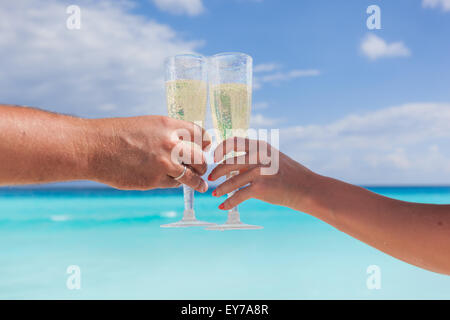 Klingende Gläser mit Champagner am Sandstrand und Meer Hintergrund, geringe Bautiefe Stockfoto