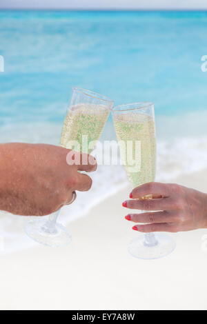 Klingende Gläser mit Champagner am Sandstrand und Meer Hintergrund, geringe Bautiefe Stockfoto