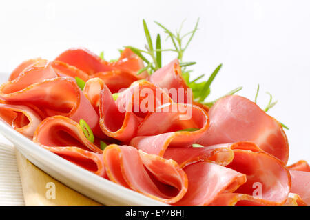 Dünne Scheiben von geräuchertem Schweinefleisch auf Platte angeordnet Stockfoto