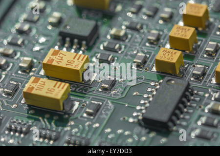 Makrofoto der Leiterplatte (PCB) mit gelben Tantal-Oxidkondensatoren (eine Seltene Erden). Nahaufnahme des Schaltkreises, Detail einer Leiterplatte. Stockfoto