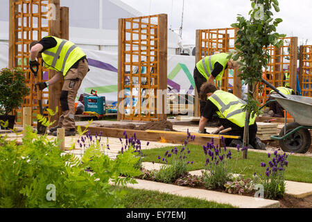 Garten- und Landschaftsarbeiter Ausbildung im Tatton Park, Cheshire, Großbritannien Juli 2015. Letzte Feinheiten auf dem jährlichen RHS Blumenfestival 17th Showground als Lehrlinge in Landschaftsbau und Gartenbau demonstrieren ihre Lehrkünste über drei Tage Herstellung identischer Grundstücke in einem unfertigen kleinen Garten mit Spalier und Pflaster. Stockfoto