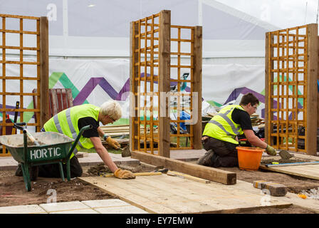 Garten- und Landschaftsarbeiter Ausbildung im Tatton Park, Cheshire, UK 23. Juli 2015. Letzte Feinheiten beim 17. Jährlichen RHS Flower Festival Showground als Lehrlinge im Landschaftsbau und Gartenbau ihre Lehrkünste demonstrieren, indem sie Gartenreliis installieren und identische Parzellen in einem unfertigen kleinen Terrassengarten mit Pfosten und Pflastersteinen herstellen. Stockfoto