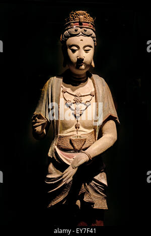 Eine antike chinesische gemalte Tonskulptur eines stehenden Bodhisattva aus der Song-Dynastie (960–1279 n. Chr.), die ein raffiniertes Halskette-Ornament, elegante Vorhänge und eine hohe dekorative Krone trug, die vor einem dunklen Hintergrund in der Galerie der antiken chinesischen Skulpturen im Shanghai Museum in Shanghai, China, aufgenommen wurde Stockfoto