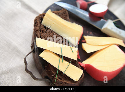 Scheiben Gouda-Käse mit Schwarzbrot und Schnittlauch auf Schneidebrett mit Platz für text Stockfoto