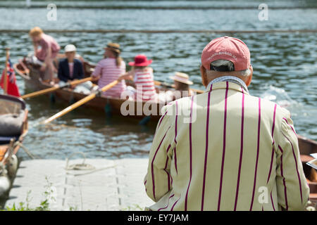 Mann in eine gestreifte Jacke, die gerade einer Familie ein Ruderboot auf der Themse traditionellen Boat Festival, Henley On Thames, Oxfordshire, England Stockfoto