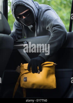 Verkehrskonzept Verbrechen. Dieb stiehlt Tasche aus dem Auto Stockfoto