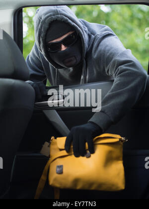 Verkehrskonzept Verbrechen. Dieb stiehlt Tasche aus dem Auto Stockfoto