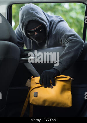 Verkehrskonzept Verbrechen. Dieb stiehlt Tasche aus dem Auto Stockfoto