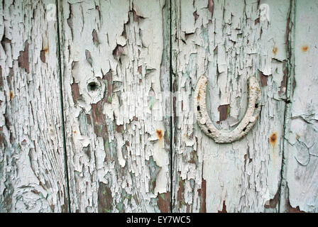 Hufeisen an alte abgenutzte Tür genagelt / Peeling Holzarbeiten Stockfoto