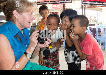 Yangon, Myanmar - 5. Mai 2014: Eine touristische zeigt jungen burmesischen Kinder ihre Foto. Kinder sind neugierig, Ausländer zu treffen. Stockfoto