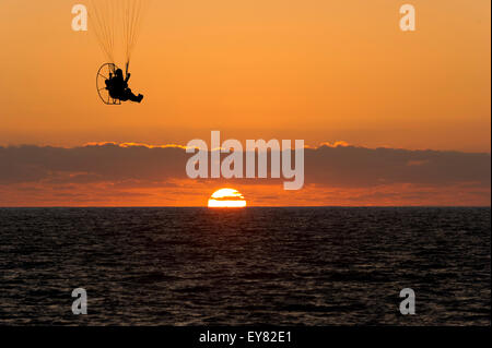 Gleitschirm mit detaillierten Rutsche Linien ist gegen einen orangefarbenen Himmel Wolkengebilde mit den Sonnenuntergang am Meer Horizont abhebt. Stockfoto