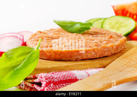 Rohe Burger Patty und geschnittene Gemüse auf Schneidebrett Stockfoto