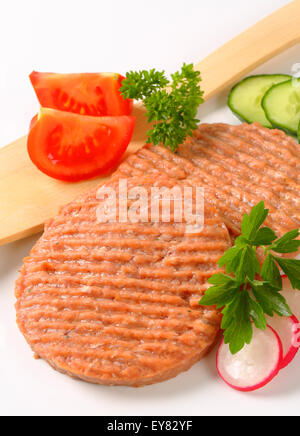 Studioaufnahme von Roh Burger Bratlinge und geschnittenem Gemüse Stockfoto