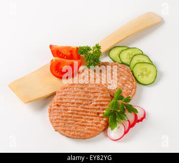 Studioaufnahme von Roh Burger Bratlinge und geschnittenem Gemüse Stockfoto