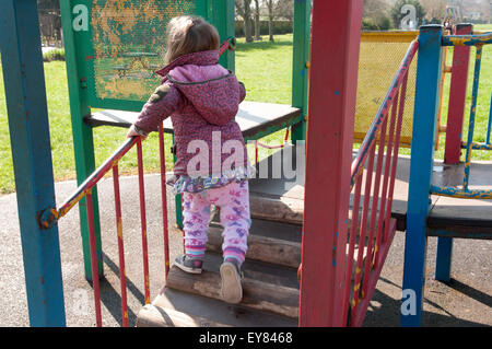 Kleinkind spielt auf einem Klettergerüst im park Stockfoto