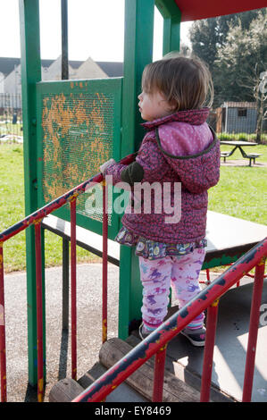 Kleinkind spielt auf einem Klettergerüst im park Stockfoto