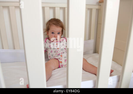 Babymädchen auf der Suche durch die Gitterstäbe ihr Kinderbett schauen ängstlich Stockfoto