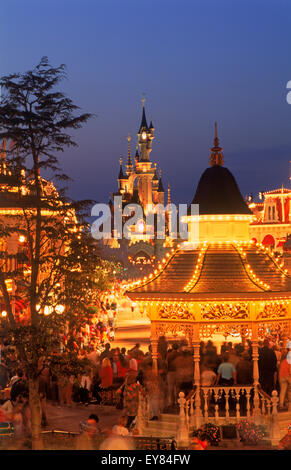 Das Schloss mit Main Street mit ihren Geschäften und Menschen in der Dämmerung Licht im Euro Disney Resort außerhalb von Paris Stockfoto