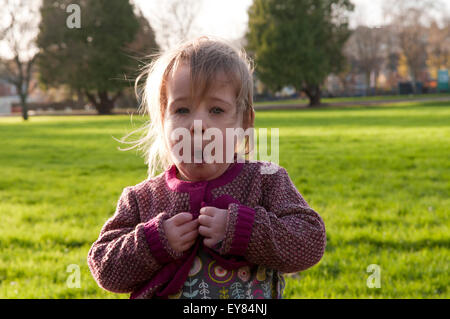 Mädchen versuchen ihre Tasten auf ihrer Strickjacke zu tun, bis Stockfoto