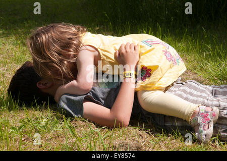 Kleines Mädchen umarmt, spielen mit jungen Stockfoto