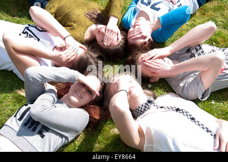 Glückliche Gruppe von Mädchen im Teenageralter liegen in einem Kreis mit ihren Händen über ihre Augen Stockfoto