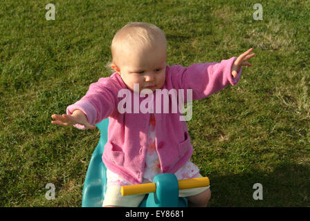 Babysitting auf Plastikspielzeug zu erreichen Stockfoto