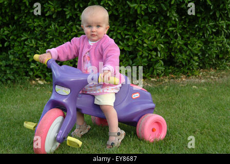 Glücklich Kleinkind sitzt auf einem Kunststoff Dreirad Stockfoto