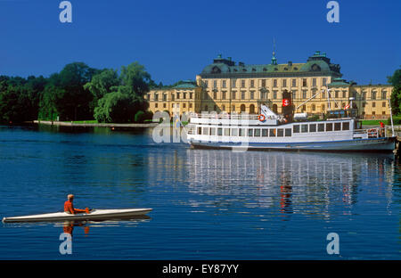 Fähre und Kajak auf ruhigem Wasser vor der königlichen Residenz in Drottningholm Palace in der Nähe von Stockholm an Sommertag Stockfoto