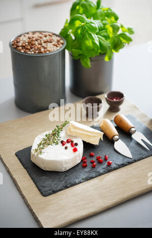 Der Geschmack von Frankreich, direkt auf einem Brett. Eine frische, perfekte Camembert Käse sitzt bereit, auf einer Schiefertafel Tafel gegessen werden. Es ist dekoriert mit frischen Rosmarin und Granatapfel Samen. Stockfoto