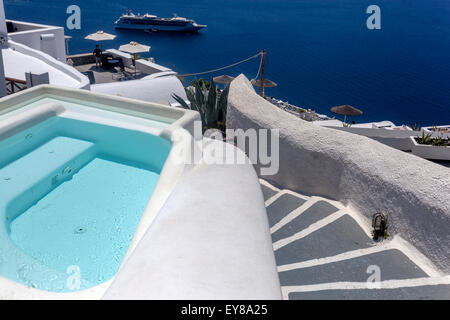 Privater Luxus-Whirlpool und weiße Treppe mit Blick auf die Caldera mit einem Kreuzfahrtschiff in Imerovigli, Santorin, Griechenland. Luxuriöse Urlaubsstimmung Stockfoto