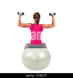 Sportliche Frau auf einem Gymnastik-Ball dabei Training mit Hanteln Stockfoto