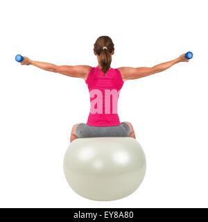 Sportliche Frau auf einem Gymnastik-Ball dabei Training mit Hanteln Stockfoto