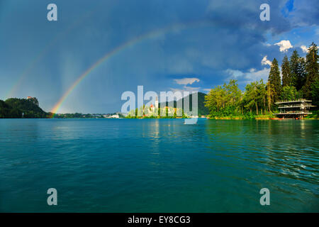 Doppelter Regenbogen über dem Bleder See Insel Kirche als Sturm weht über Slowenien. Stockfoto