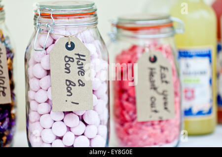 Verschiedene Süßigkeiten in Gläsern auf einem Tisch bei einem Hochzeitsempfang. Die Trweats enthalten Bon Bons und sind alle mit handgeschriebenen Etiketten gekennzeichnet Stockfoto